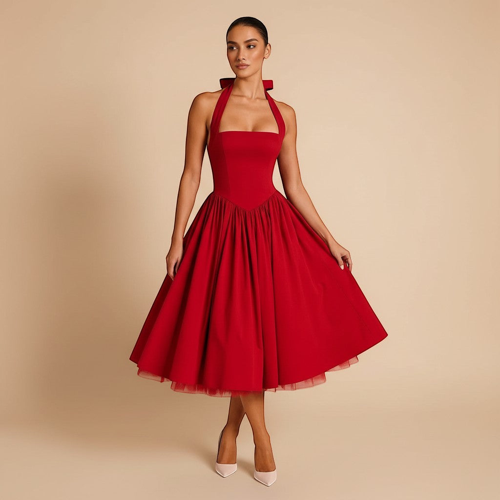 Yemelia red halter neck fit and flare midi dress with a structured bodice and full skirt, featuring a bow detail at the neck.